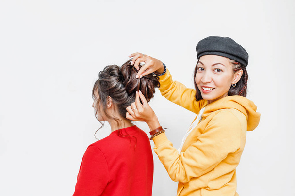 The hands of the professional female hairdresser doing Bridal or evening hairstyle with curls for her client in studio - 写真・画像