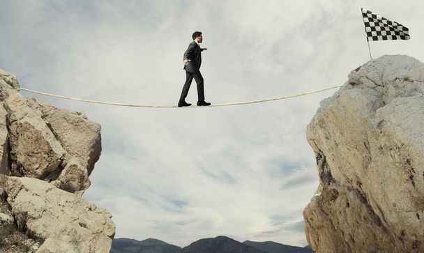 Business concept of businessman who overcome the problems reaching the flag on a rope - Photo, Image