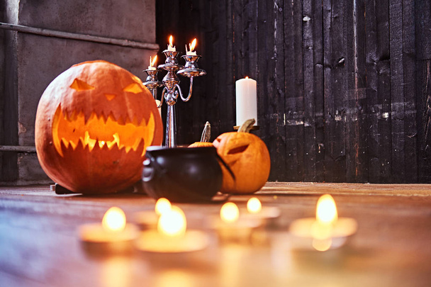 Страшные тыквы и свечи на деревянном полу в старом доме
. - Фото, изображение