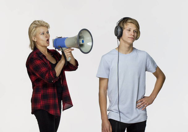 Misunderstandings in family. Angry mother with megaphone talking to her male teenager - Foto, imagen
