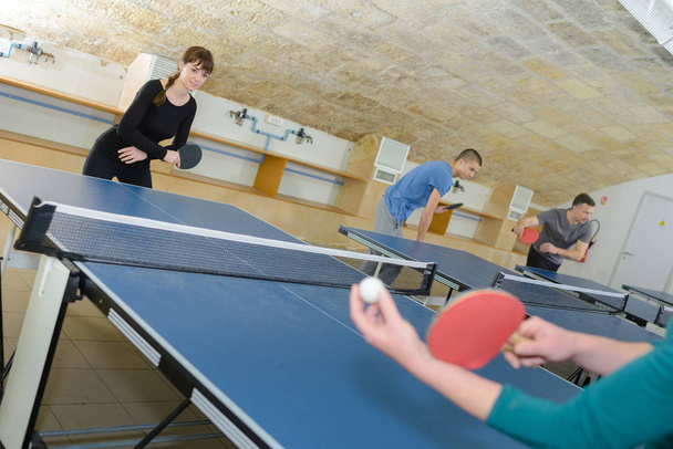pretty woman playing ping-pong with friends - Photo, Image