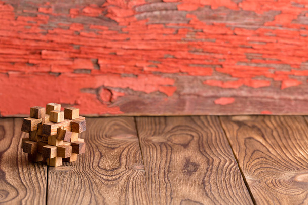 Rompecabezas de madera entrelazado intrincado sobre un fondo rústico de madera con pintura descascarada roja y espacio de copia
 - Foto, imagen