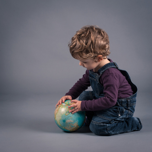 Little kid playing with globe. Studio shot. - Fotoğraf, Görsel