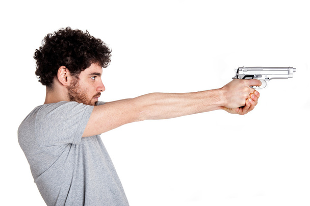 Young killer pointing a gun over white background. - Fotografie, Obrázek