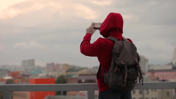 Man tourist make mobile photos of sky and cityscape standing on a terrace - Záběry, video
