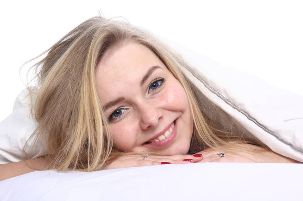 Beautiful young girl is lying on bed and smiling - Fotó, kép