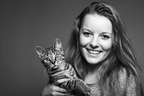 Young blonde girl holding a cat on black and white tone - Zdjęcie, obraz