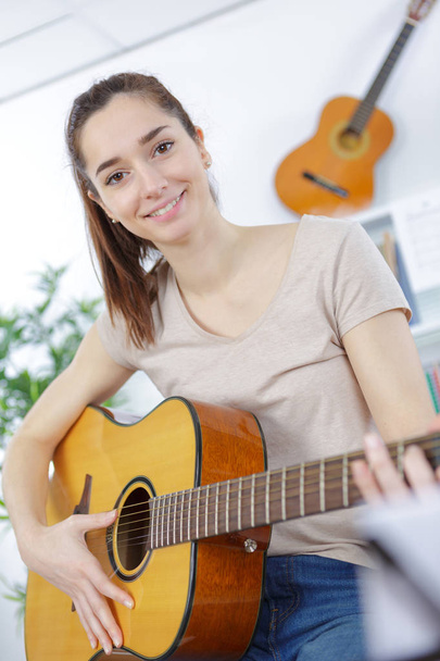 beautiful girl teenager in shirt and torn jeans playing guitar - Foto, Imagen