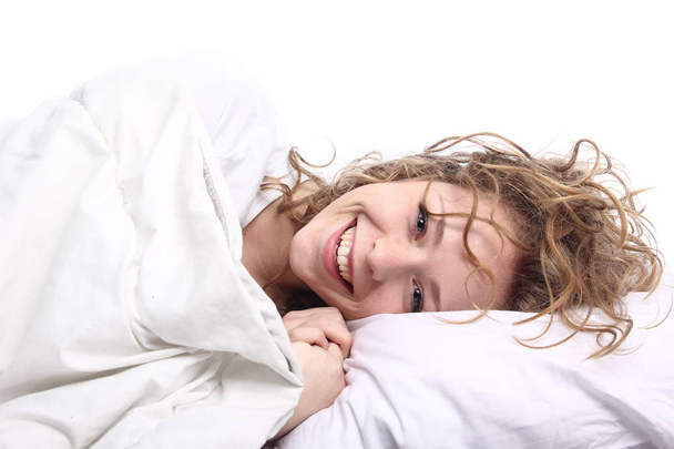 Beautiful young girl is lying on bed and smiling - Foto, immagini