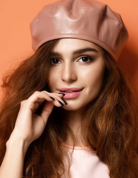 brunette woman in leather beret hat on orange background - Zdjęcie, obraz