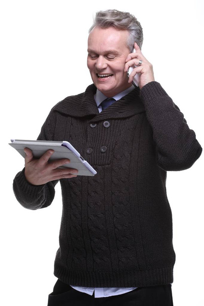 Old caucasian man is talking on mobile phone and using tablet PC - Foto, imagen