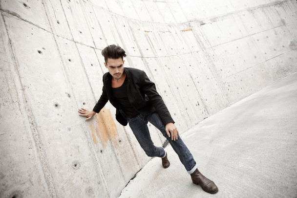 Attractive man dressed in jeans and boots in a grungy scenary - Foto, imagen