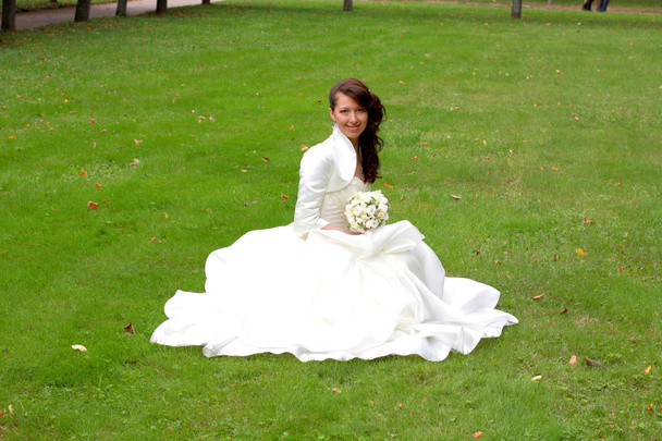 Szczęśliwa panna młoda siedzi na trawie - Zdjęcie, obraz