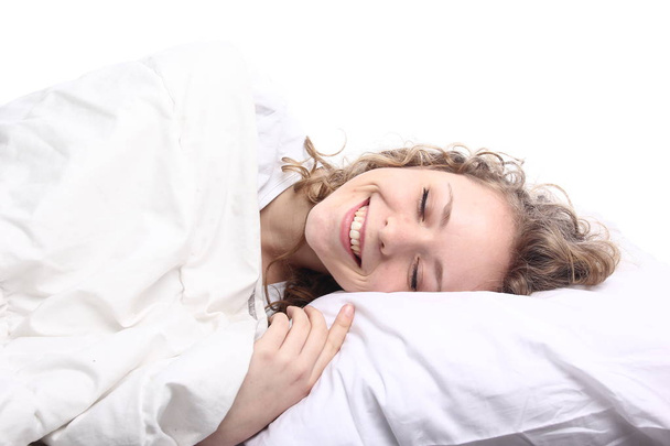 Beautiful young girl is lying on bed and smiling - Valokuva, kuva