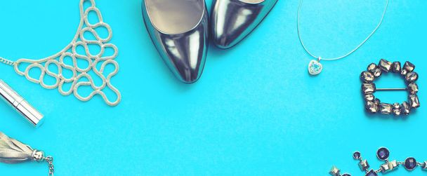 Transparent zestaw akcesoriów mody lay płaskie buty torebka naszyjnik Biżuteria szminka klamra srebrny kolor na niebieskim tle. Widok z góry miejsce - Zdjęcie, obraz