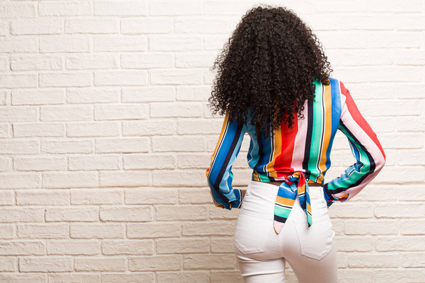 Jeune femme noire en chemise colorée montrant le dos, posant et attendant, vue arrière
 - Photo, image