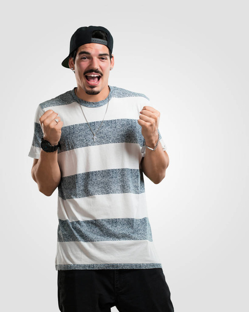 Giovane rapper uomo molto felice ed eccitato, alzando le braccia, celebrando una vittoria o un successo, vincendo la lotteria
 - Foto, immagini