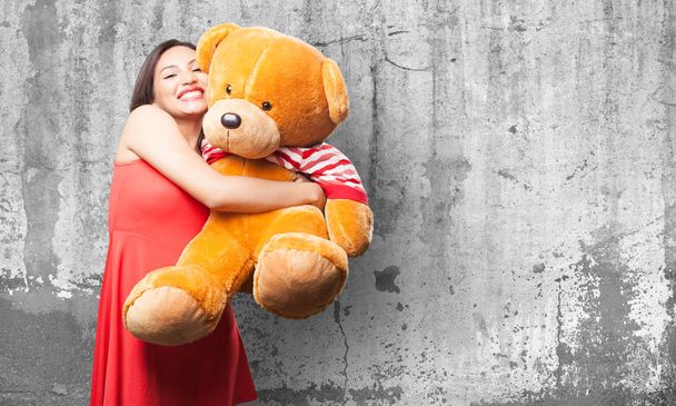 asian woman in red dress holding a teddy bear against grey grunge background - 写真・画像