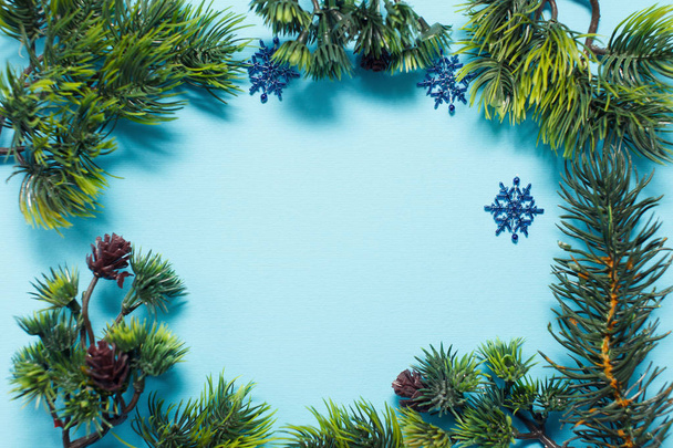 Branches of fir, cones and snowflakes on blue paper background with copyspace for text. Christmas or New Year's card. - Фото, изображение