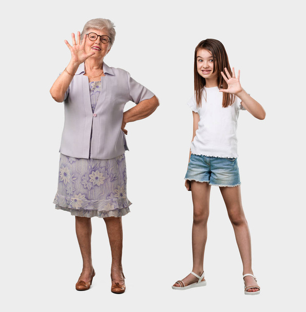 Full body of an elderly lady and her granddaughter showing number five, symbol of counting, concept of mathematics, confident and cheerful - Photo, Image