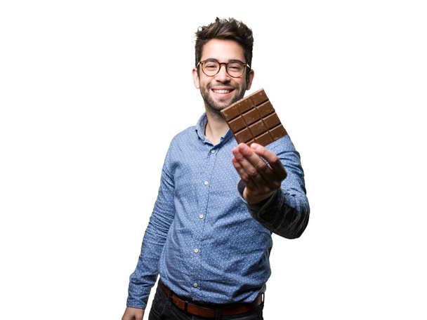 young man holding a chocolate bar isolated on white background - Foto, Imagem