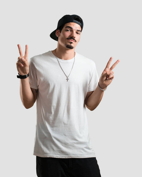 Young rapper man fun and happy, positive and natural, makes a gesture of victory, peace concept - Фото, изображение