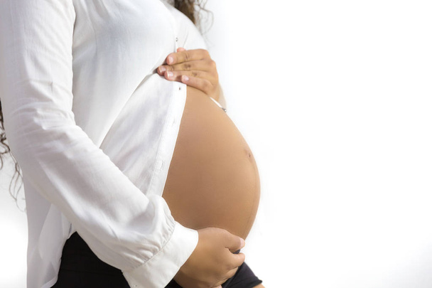 Közelkép stúdió lő a terhes nő megérintette a hasa. elszigetelt fehér background - Fotó, kép