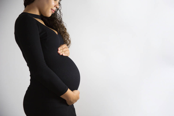 Nahaufnahme eines Studiodrehs, bei dem eine schwangere Frau ihren Bauch berührt. isoliert auf weißem Hintergrund - Foto, Bild