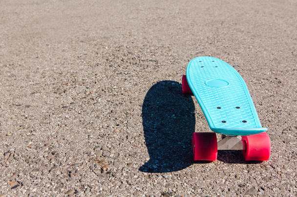 Blue plastic skateboard penny board with pink wheels stands on the track. - Foto, imagen
