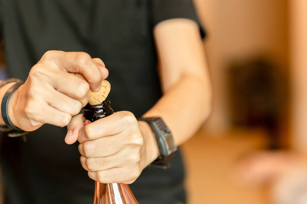 Рука відкриває пляшку шампанського для святкування в приміщенні
 - Фото, зображення