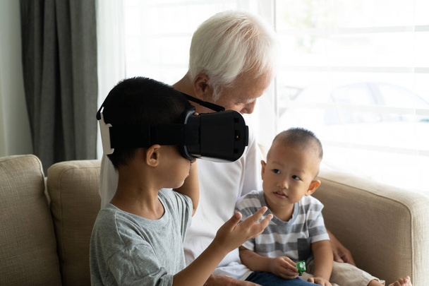 asian boy using VR goggles with grandparent technology photo - Foto, Imagen