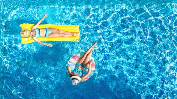 Вид з повітряного безпілотника на дітей у басейні зверху, щасливі діти плавають на надувному кільцевому пончику та матраці, дівчата розважаються у воді на сімейному відпочинку на курорті
 - Фото, зображення