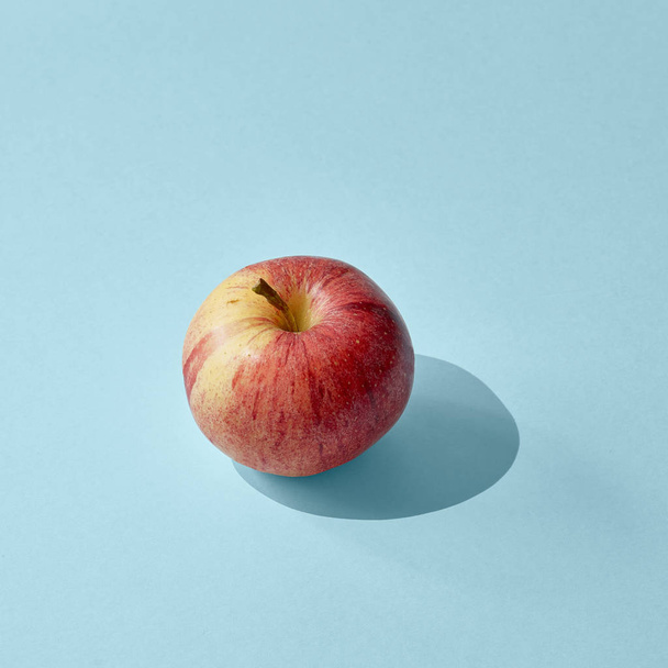 Apple a hosszú, éles árnyék a kék háttér - Fotó, kép