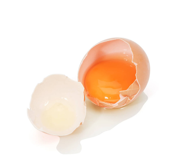 huevo agrietado con cáscara de huevo, yema de huevo en una cáscara de huevo aislada sobre fondo blanco
. - Foto, Imagen