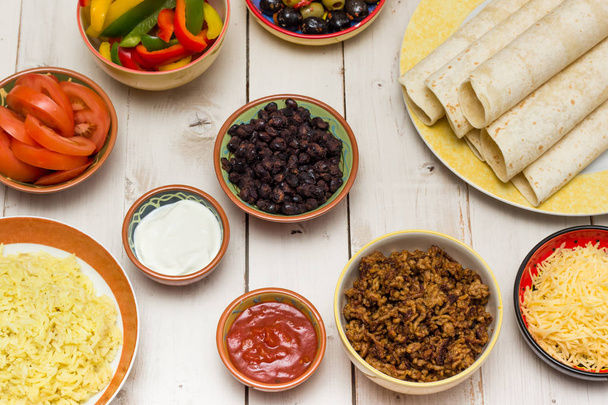 Ingredients to make mexican burritos with tortillas, rice, cheese, ground beef, tomato, black beans - Photo, Image