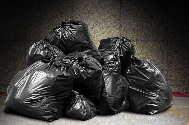 vuilnis is stapel veel dump, veel plastic vuilniszakken zwart op betonnen muur, vervuiling door afval plastic afval vuilnis, afval zakken bin van plastic afval, stapel vuilnis afval, veel voor ongewenste dump - Foto, afbeelding