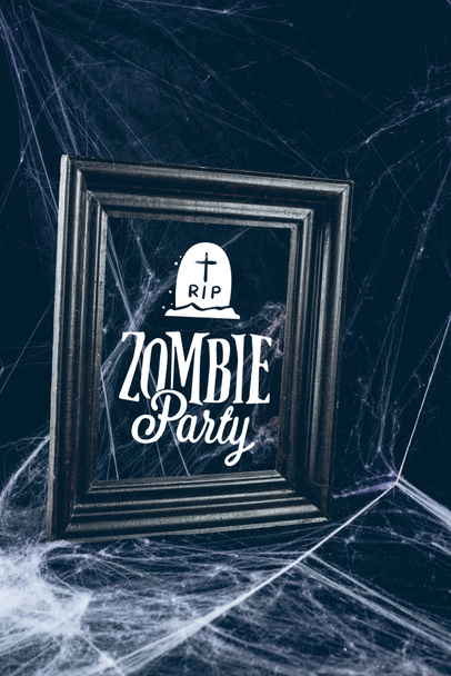black frame in spider web, creepy halloween decor with "zombie party" lettering - Fotografie, Obrázek