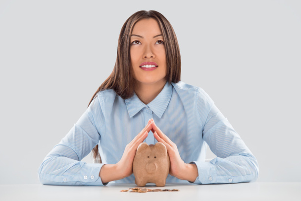 Happy business woman covering piggy bank with two hands - Foto, afbeelding