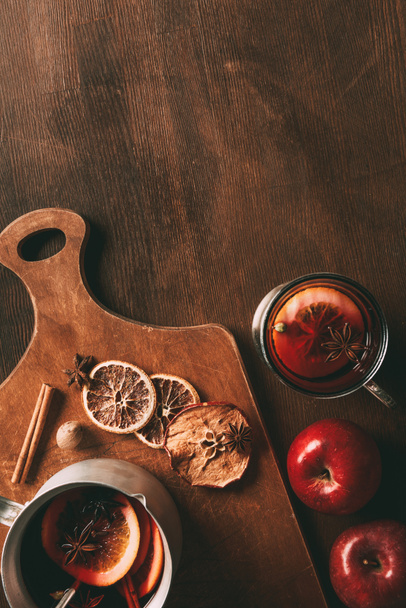 top view of homemade mulled wine with spices and apples on cutting board on wooden background - Fotó, kép