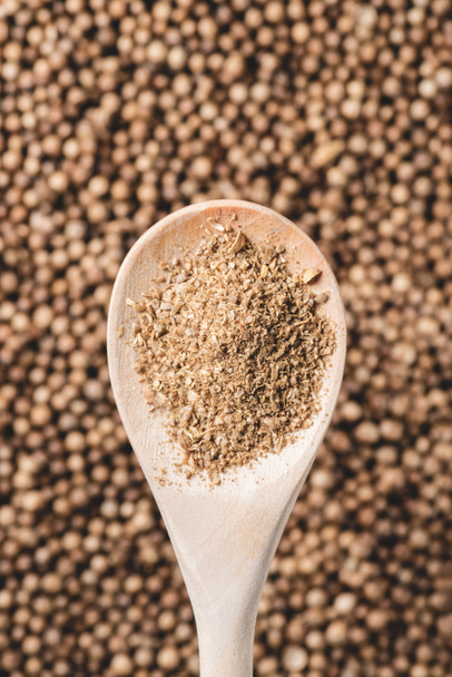 top view of wooden spoon with coriander powder and seeds - Foto, afbeelding