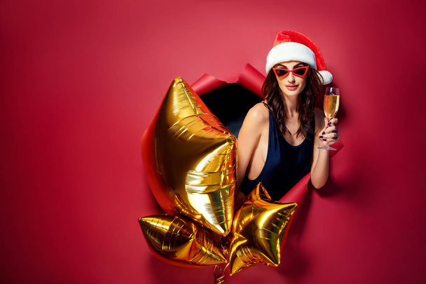 Woman in Santa hat holding golden balloons - Foto, Bild