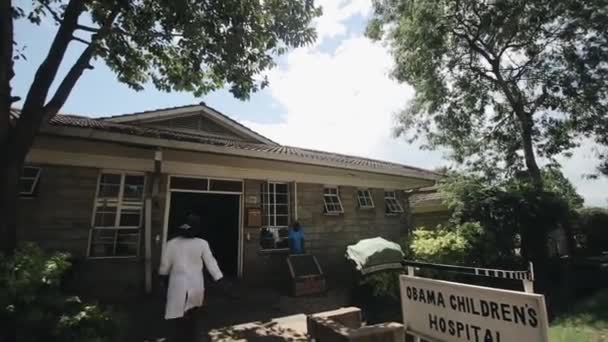 Γιατροί σε λευκές στρώσεις έρχονται στο νοσοκομείο σε μια μικρή πόλη στην Αφρική. Οι άνθρωποι πηγαίνουν να εργαστούν. - Πλάνα, βίντεο