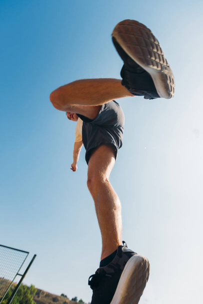 Caucasian man trains parkour while jump below sky - Foto, Imagen