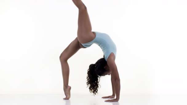 Mujer haciendo ejercicios de estiramiento y gimnasia sobre fondo blanco
 - Metraje, vídeo