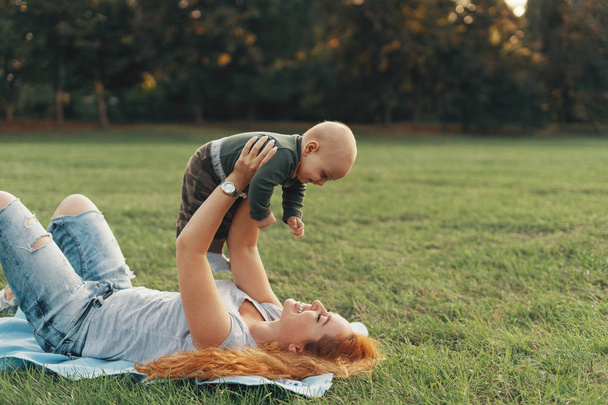 Mère heureuse allongée sur l'herbe tout en jouant avec son bébé
 - Photo, image