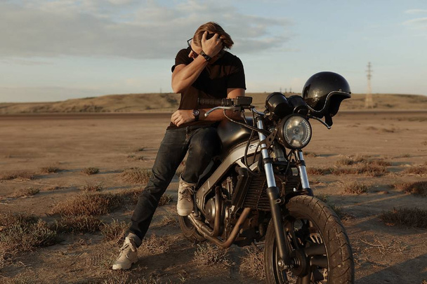 Стильный современный человек на мотоцикле, посреди пустыни, шлем, аксессуары, солнцезащитные очки, песок, шины, рискованный, свободный, открытый, прическа, спорт, отдых, приключения, образ жизни
 - Фото, изображение