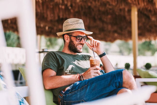 Young man drinking ice coffee in a beach bar - Photo, Image