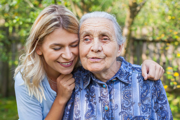 Jovem mulher atraente abraçando a velha avó ao ar livre. Feminino - gerações - amor
 - Foto, Imagem