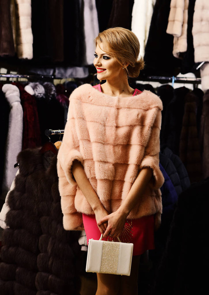 Lady holds white bag in fur shop. Winter clothing concept. - 写真・画像