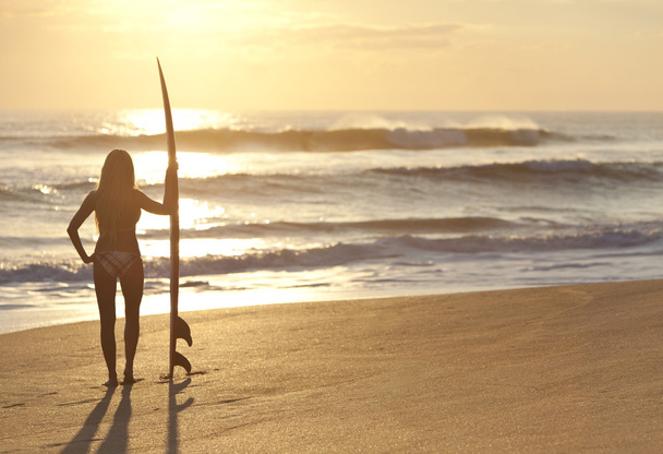 サンセット ビーチでサーフボードとビキニ姿の女性サーファー - 写真・画像